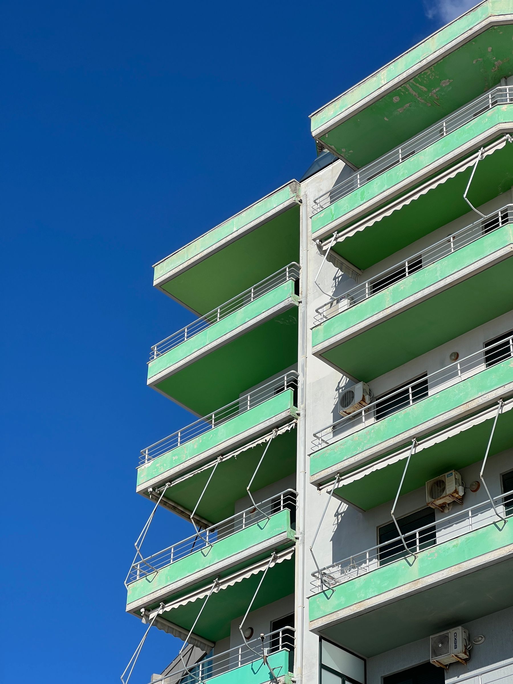 Fachada de prédio residencial com varandas em contraluz, vista de baixo contra o céu