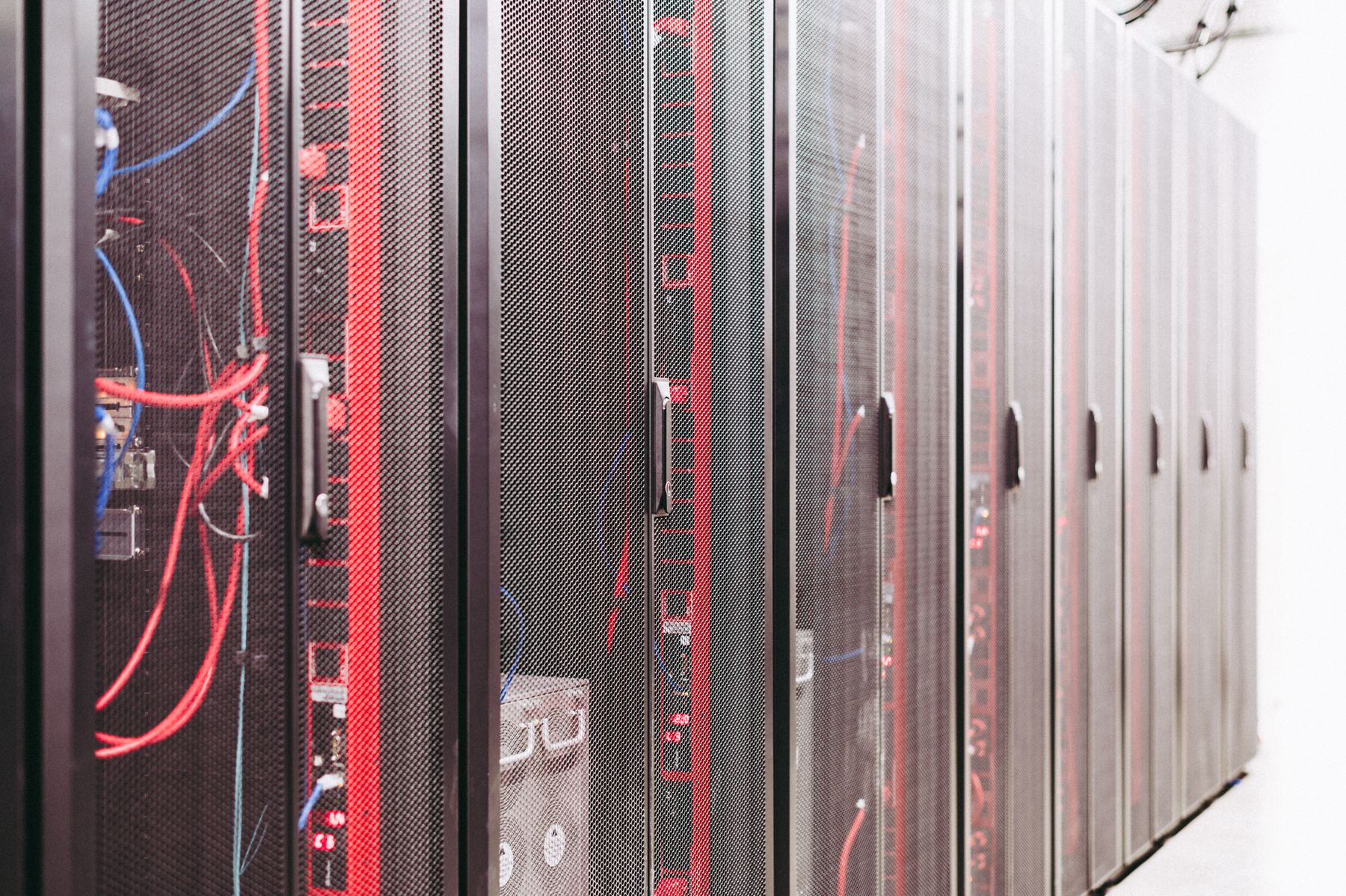 Fileira de racks de servidores em corredor de datacenter, com cabeamento de rede e luzes de status